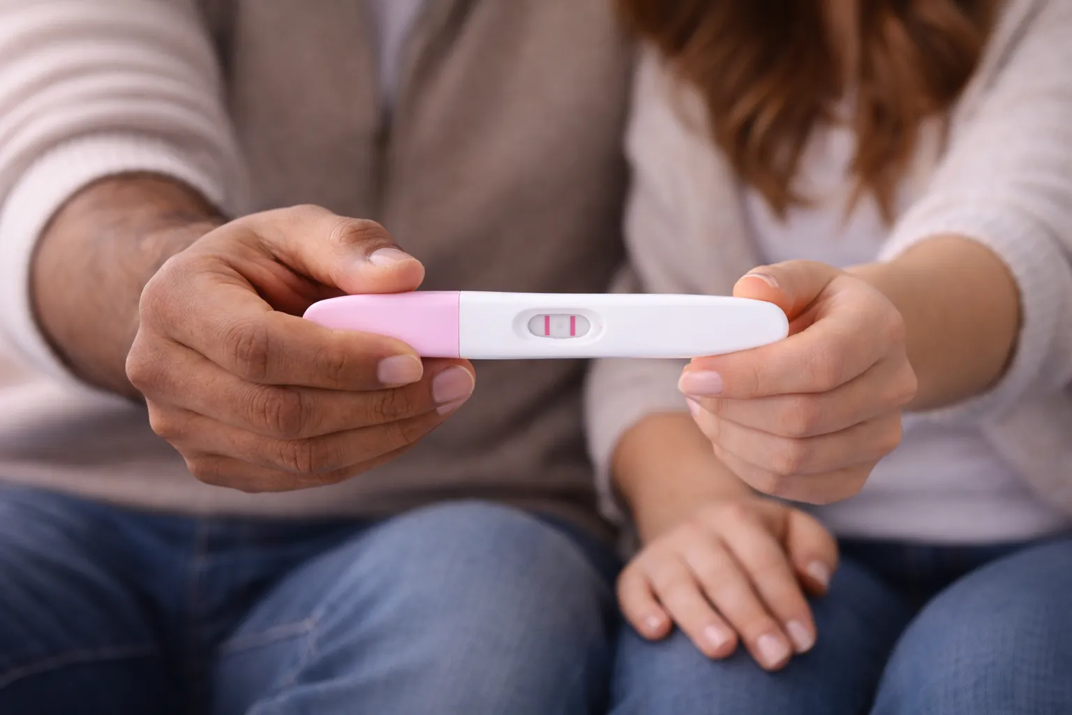 Neauglības ārstēšana - pāris ar pozitīvu grūtniecības testu rokās